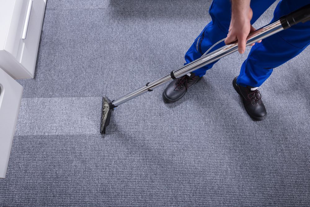 A person holding a vacuum and vacuuming the carpet   — Sadie's Cleaning Services in Koongal, QLD