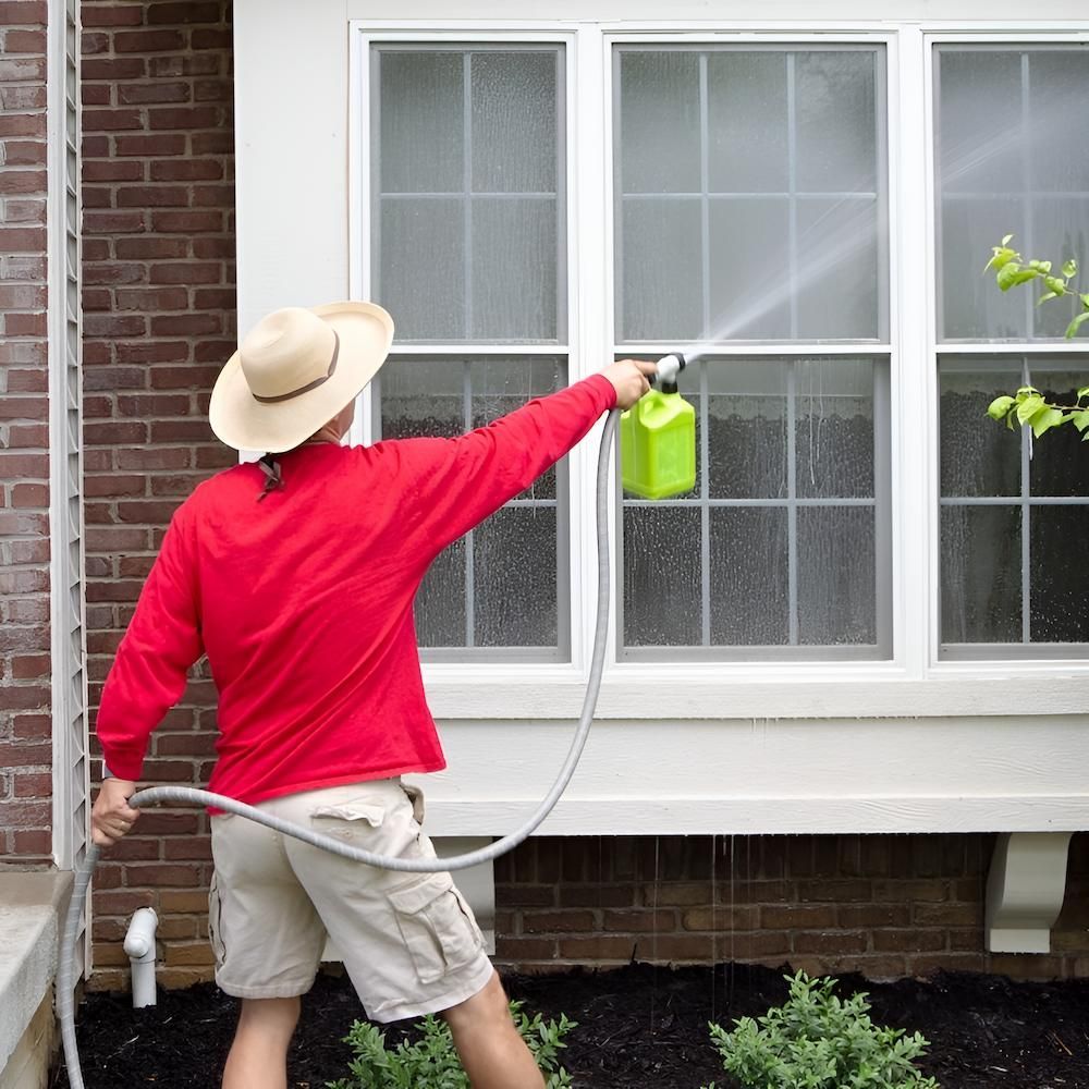A Man Spraying a Window With a Hose — Sadie's Cleaning Services in Koongal, QLD
