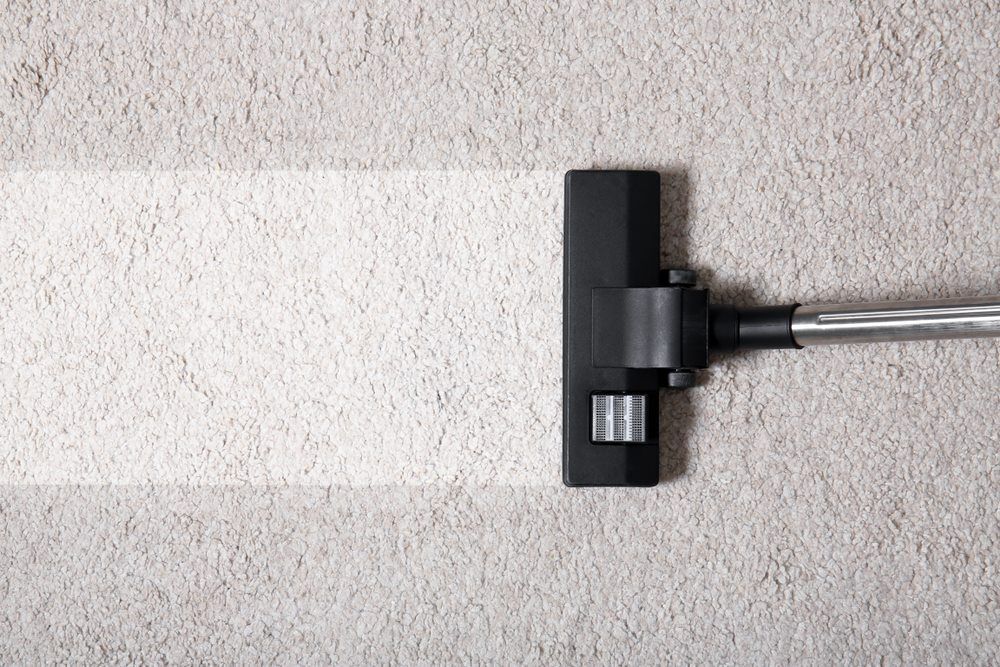 A Vacuum Cleaner Is Cleaning A White Carpet — Sadie's Cleaning Services in Yeppoon, QLD