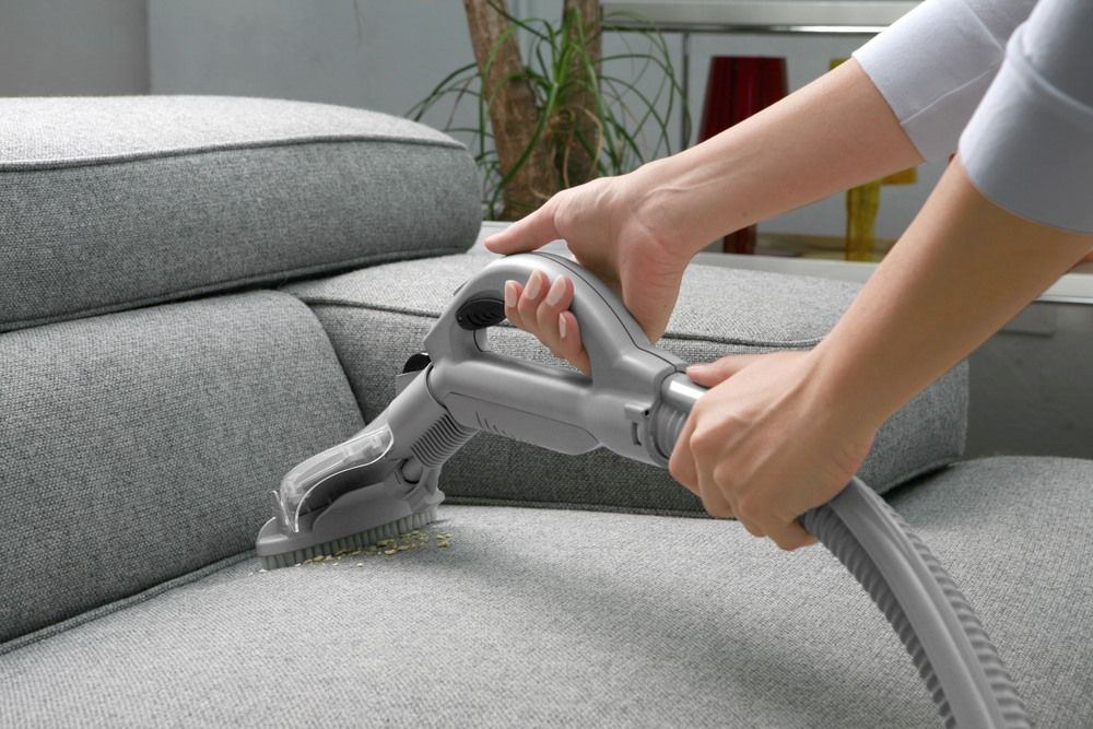 A Person Is Cleaning A Couch With A Vacuum Cleaner — Sadie's Cleaning Services in Gracemere, QLD