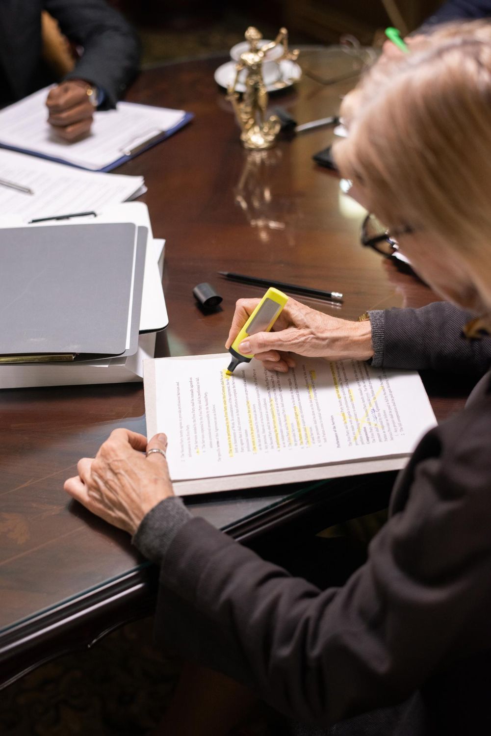 Person taking notes on a document at a meeting table with a laptop and papers nearby