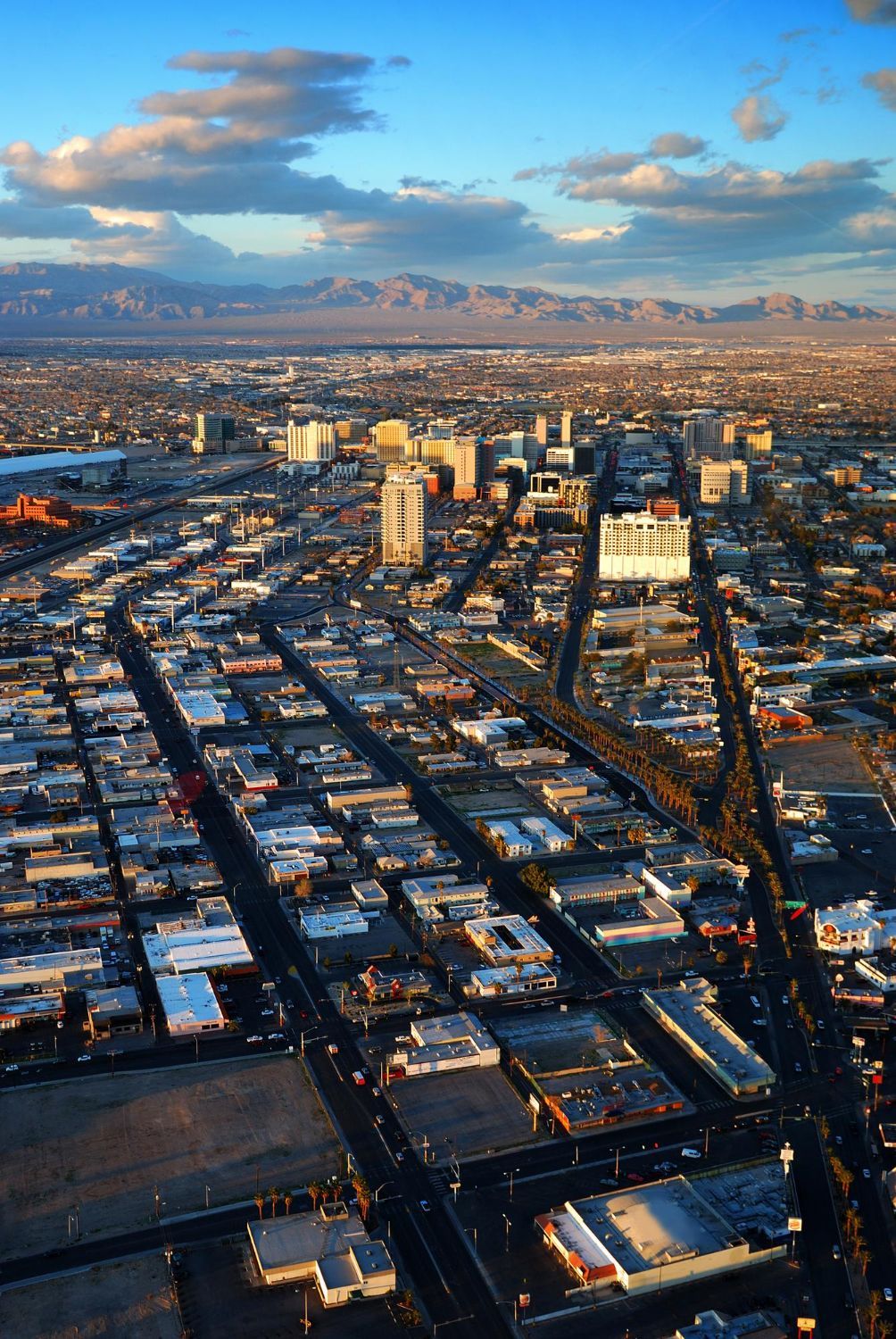 Aerial view of a dense city grid with snow-covered rooftops under a blue sky at sunset.