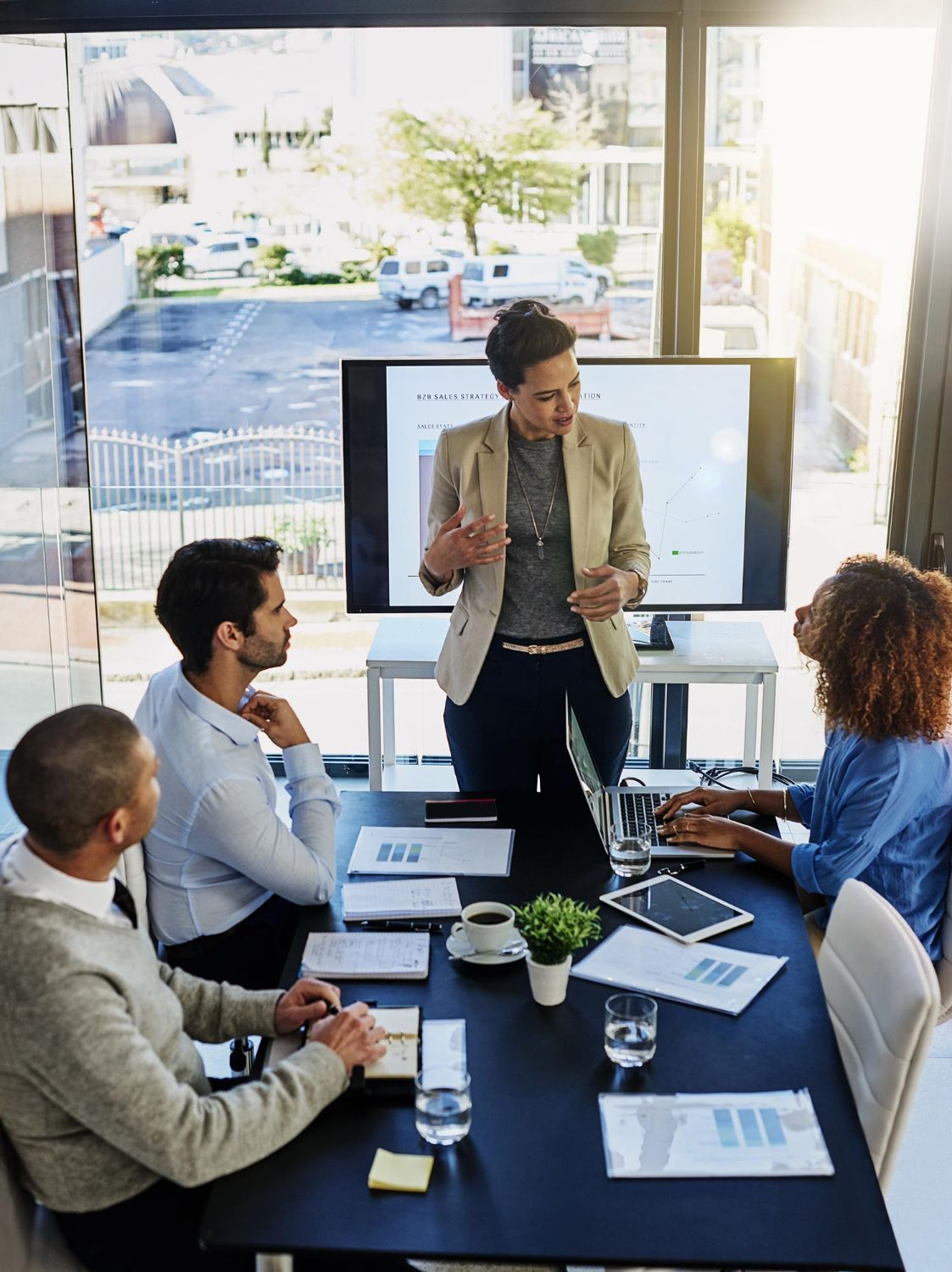 Business meeting with presenter speaking to seated colleagues in a bright conference room