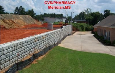 Construction site: CVS Pharmacy, Meridian, MS, with a large brick retaining wall, dirt mound, and green lawn.