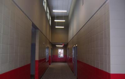 Long, narrow hallway with red and white tiled walls and fluorescent lights.