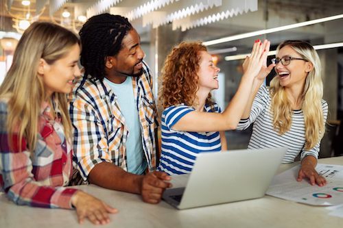 Um grupo de jovens está cumprimentando uns aos outros enquanto olham para um laptop.