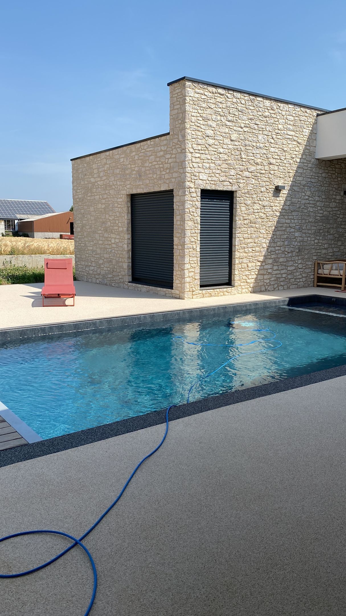 Une grande piscine se trouve devant une maison en pierre.