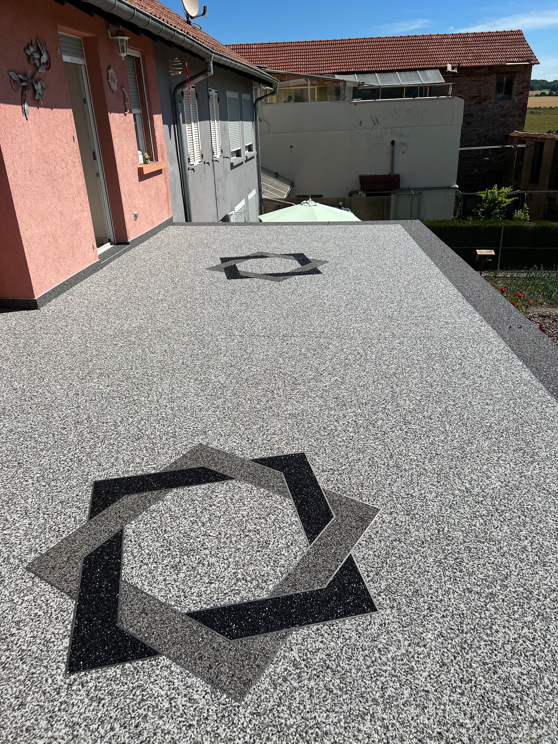 Un patio avec un design noir et blanc devant une maison.