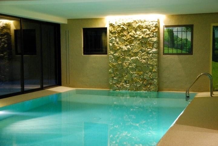 Une grande piscine intérieure avec un mur de pierre derrière elle