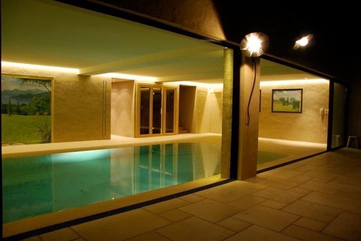 Une grande piscine intérieure est éclairée la nuit