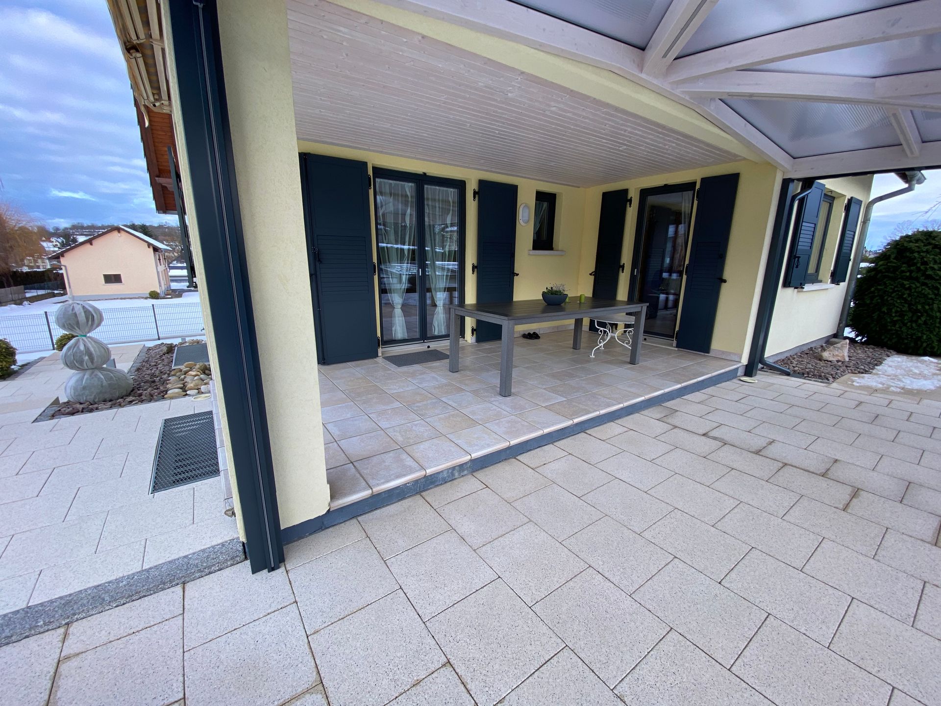 Un patio avec une table et des chaises devant une maison