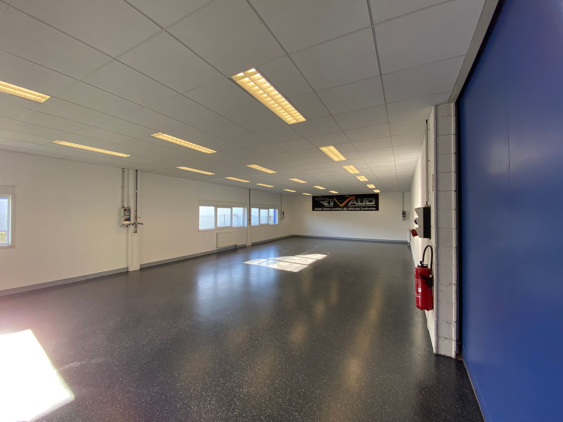 Une grande pièce vide avec un mur bleu et un extincteur