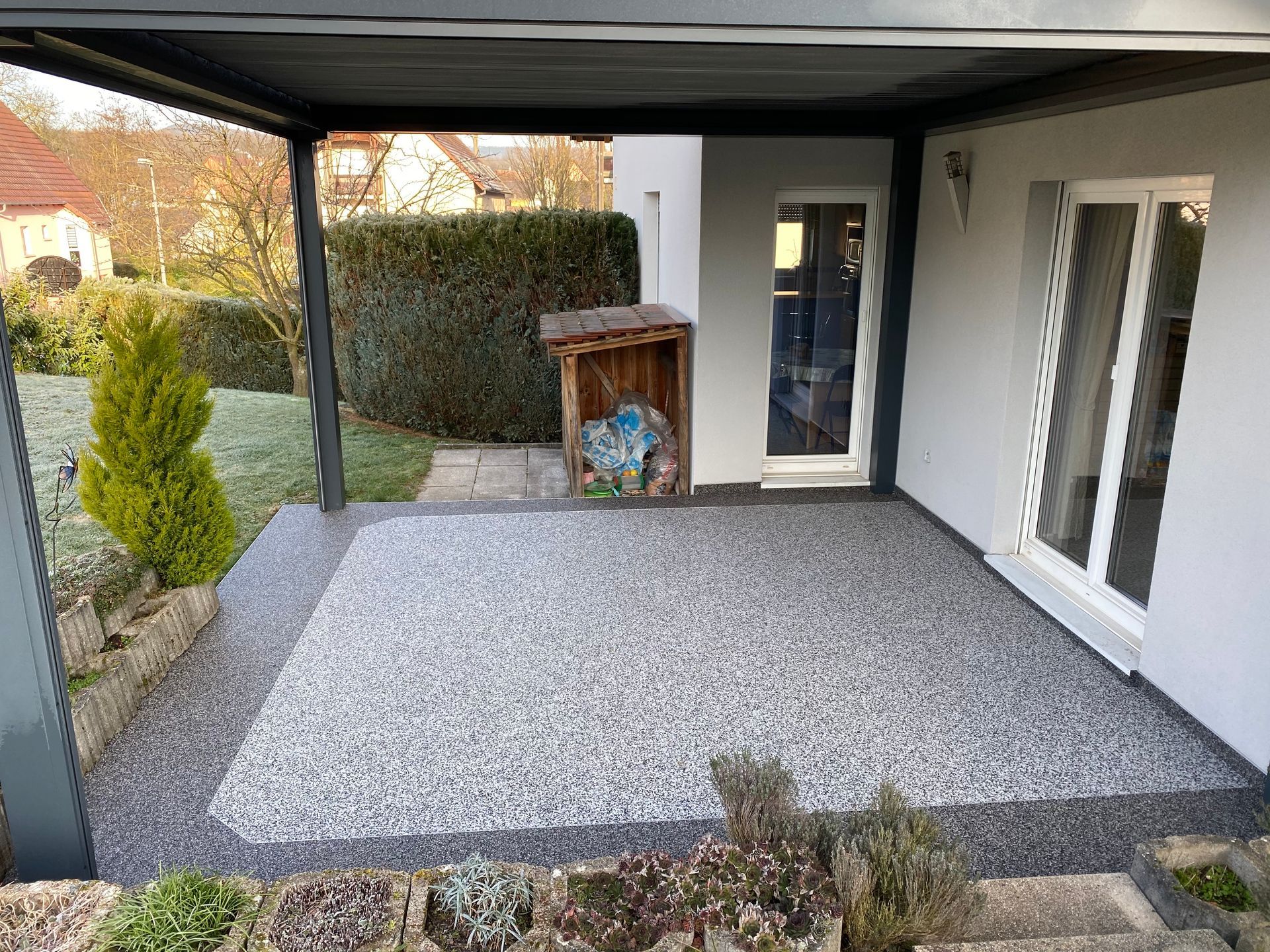 Un patio avec un auvent au-dessus et une maison en arrière-plan.