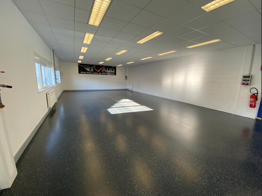 Une grande pièce vide avec un sol noir et des murs blancs.