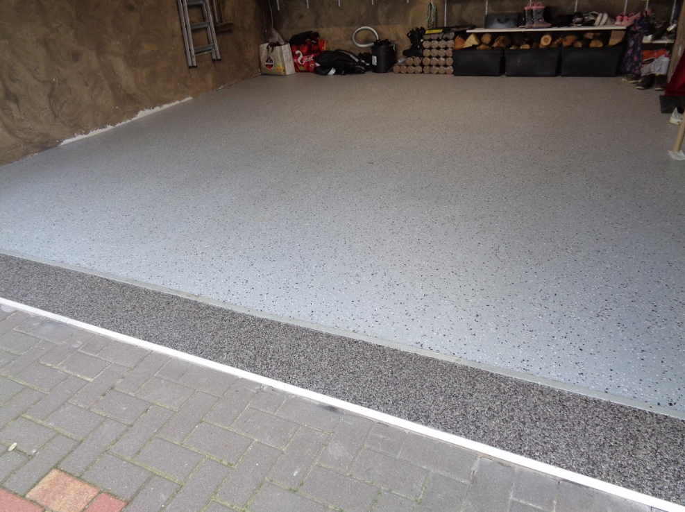 Un garage avec un sol en béton et une allée en brique.