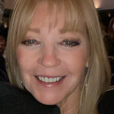 Woman with blonde hair smiling, close-up.