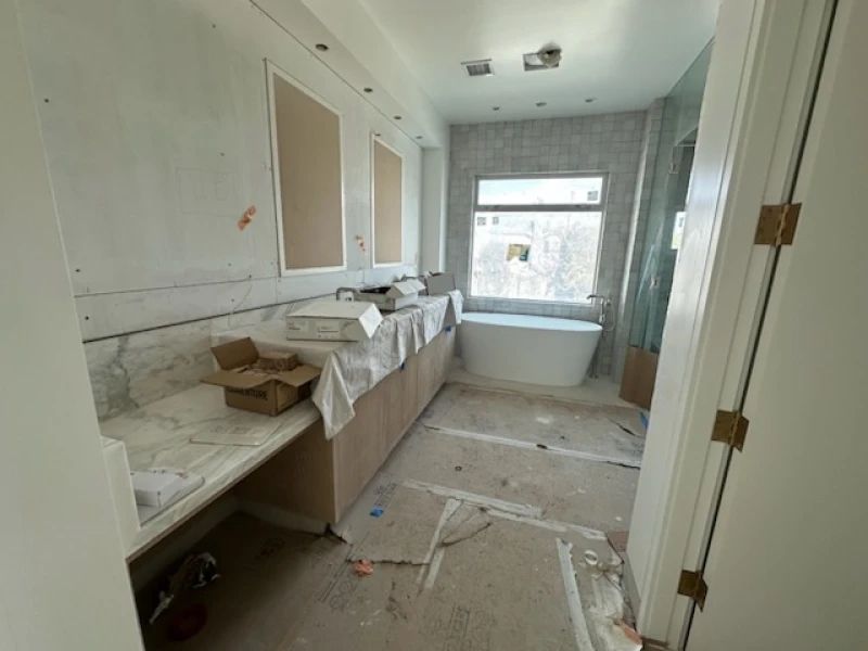 Bathroom under construction with double vanity, bathtub, and window.