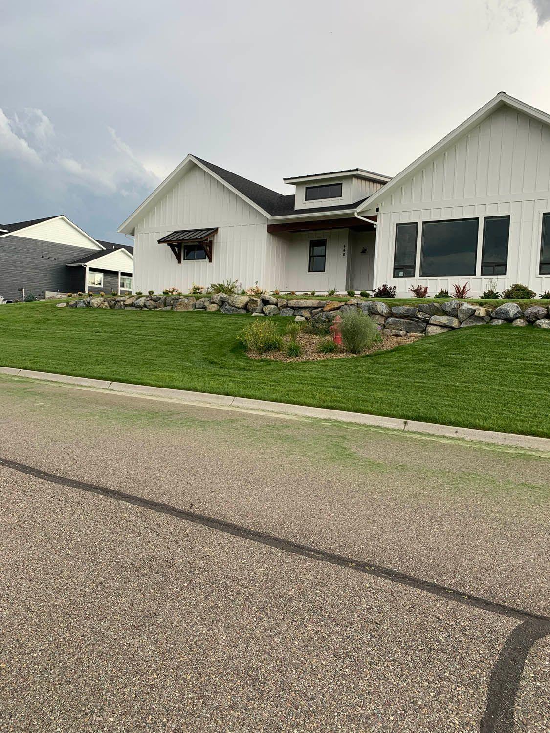 A white house with a black roof is sitting on top of a lush green hill.