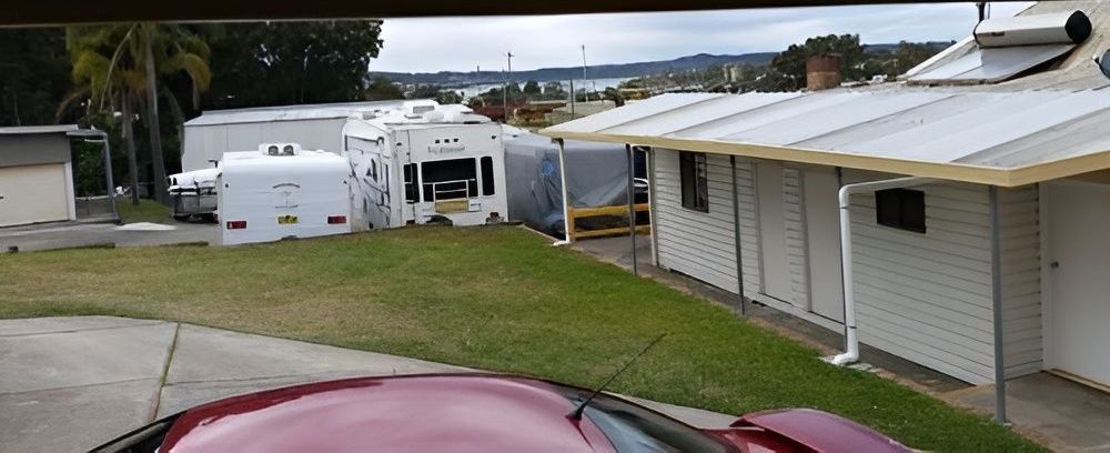 A Green Garage With a Water Tank in Front of It — Teralba Business & Storage Park in Teralba, NSW