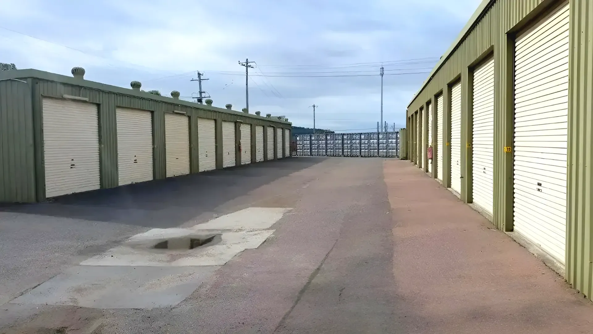 A White Metal Shed is Sitting in the Middle of a Grassy Field — Teralba Business & Storage Park in Warners Bay, NSW
