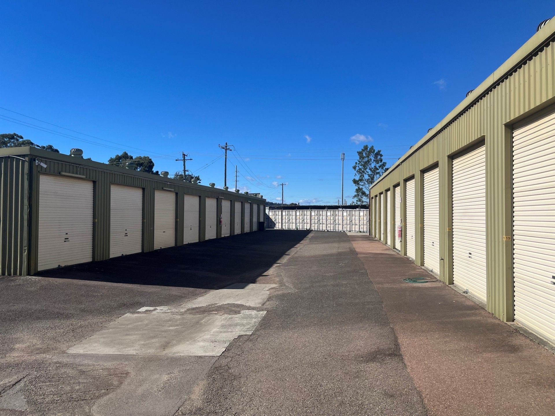 An Empty Garage With Blue Doors and a White Building — Teralba Business & Storage Park in Teralba, NSW