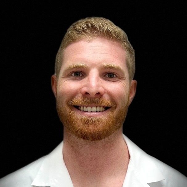 A man with a beard and a white shirt is smiling for the camera.