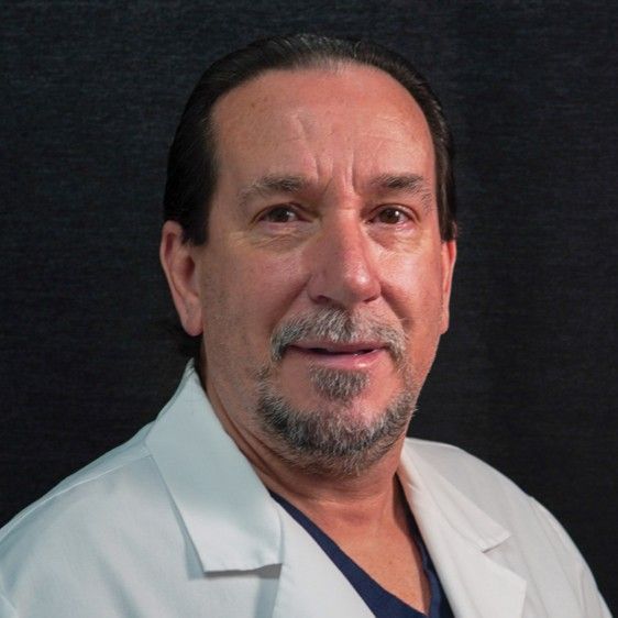 A man with a beard wearing a white lab coat