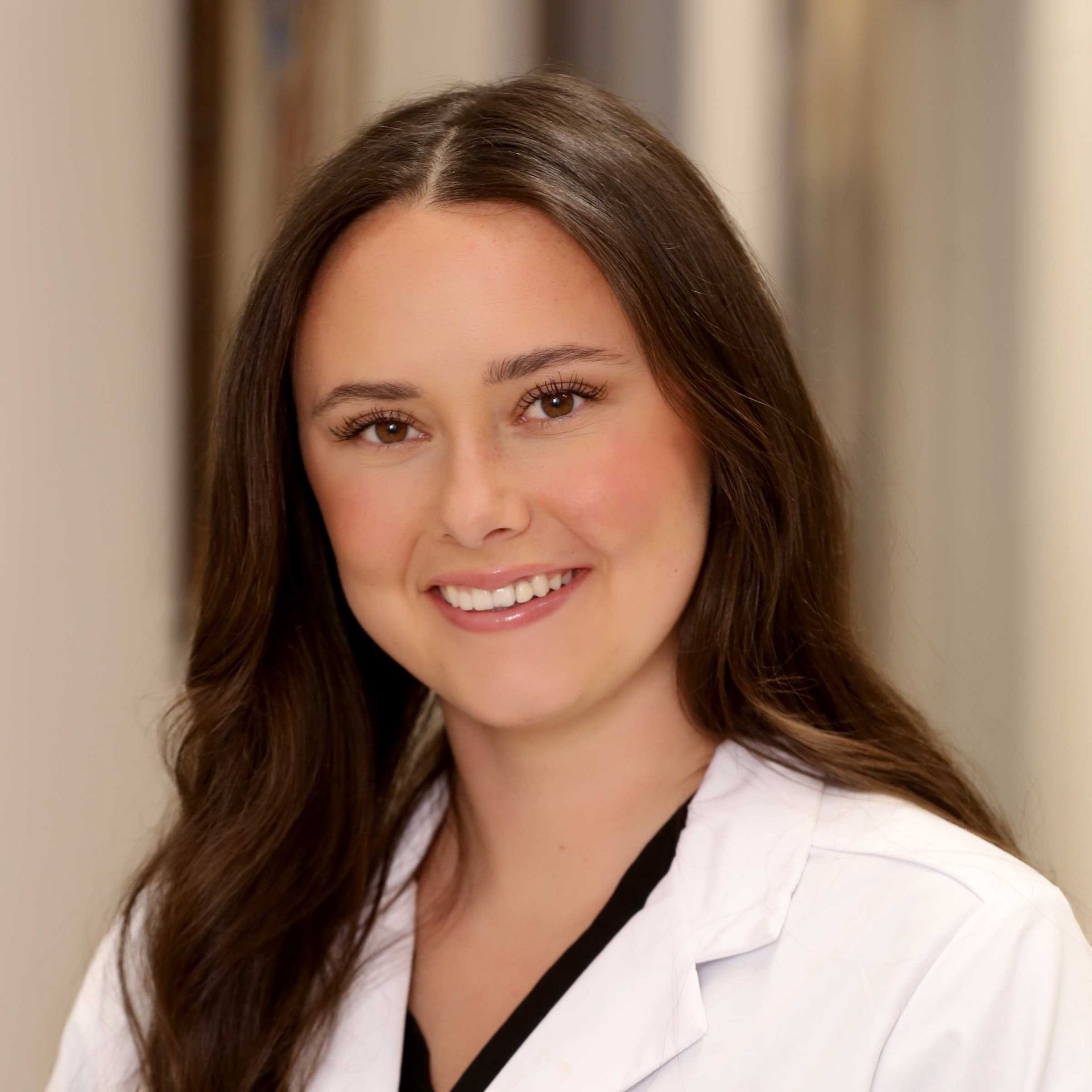 A woman in a white lab coat is smiling for the camera.