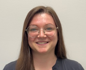 A woman in a scrub top is smiling for the camera.