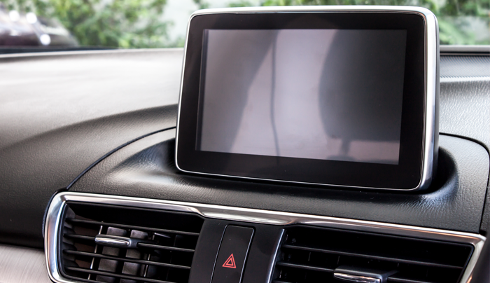 Tablero de instrumentos del automóvil con una pantalla de información y entretenimiento en blanco, ubicada encima de las salidas de aire.