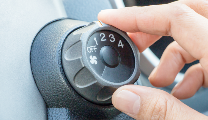 Mano girando el dial de velocidad del ventilador de un automóvil desde la posición de apagado al número 1.