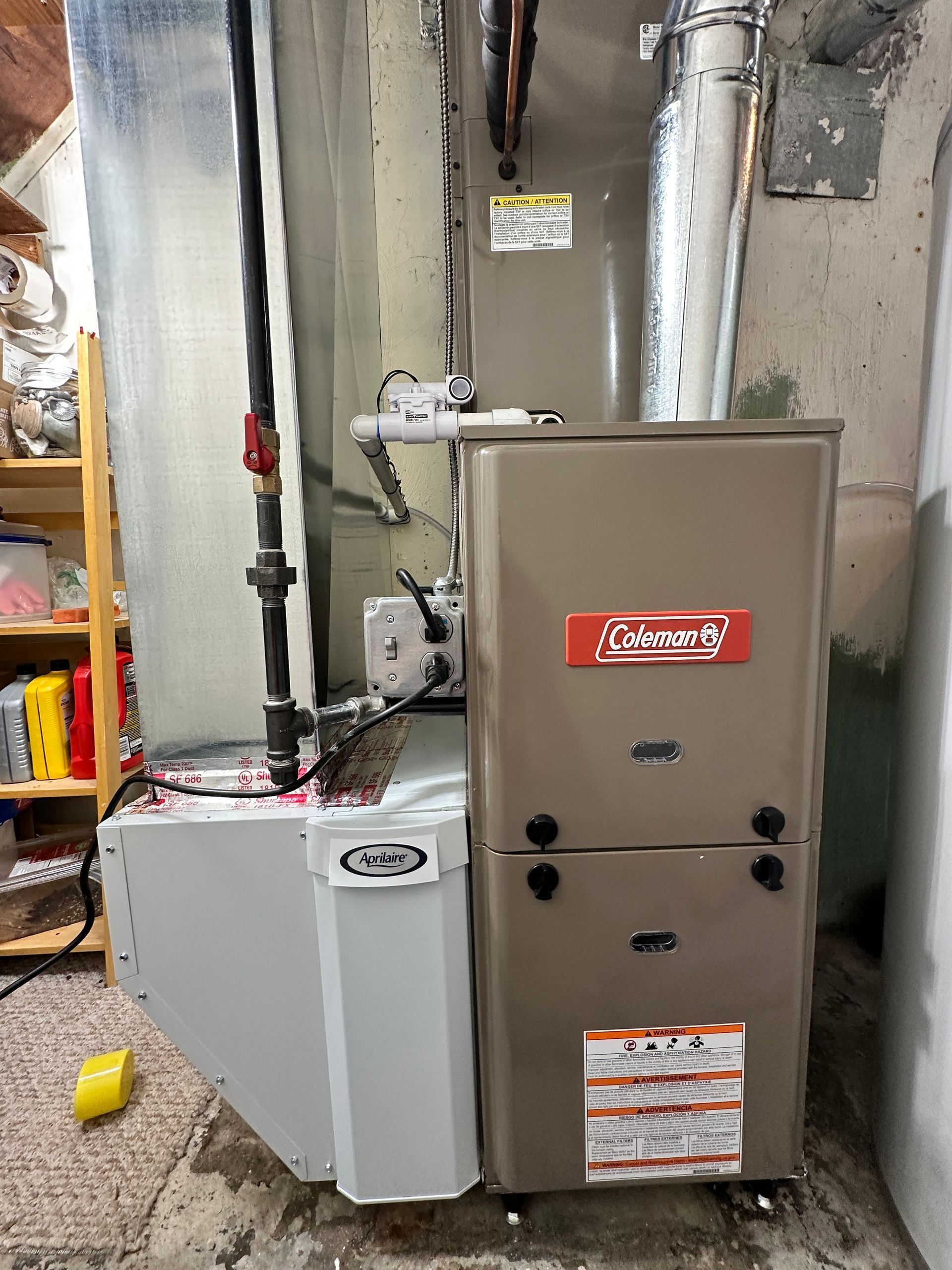 A Coleman furnace in a basement. Beige metal unit with vents and a gas line.