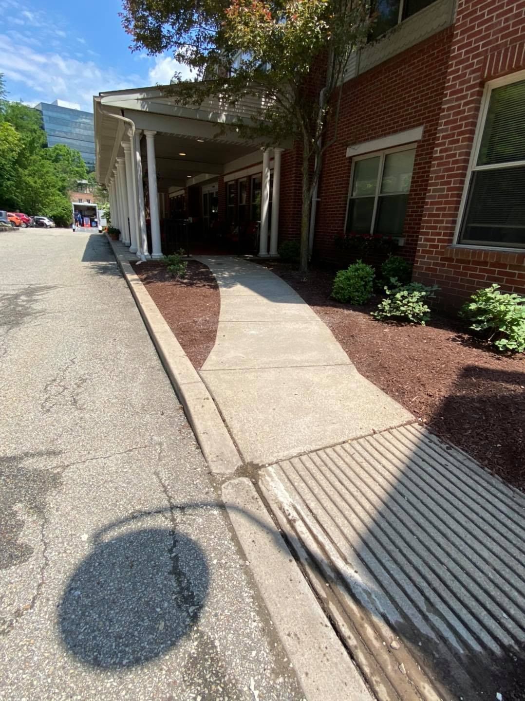 Concrete ramp leading to a building entrance under a covered walkway.
