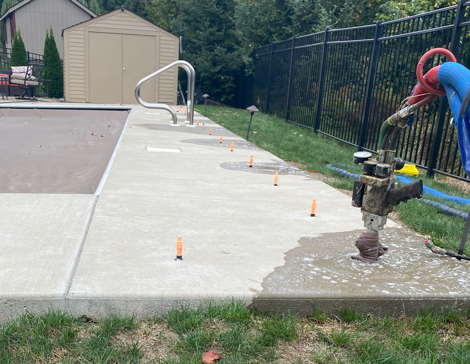 A concrete walkway curves past a rock garden and wooden fence.