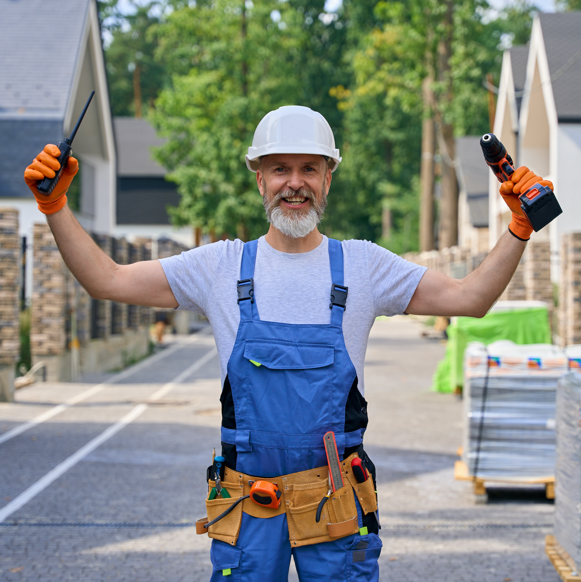 A Skilled tradesman is holding up tolls and smiling.