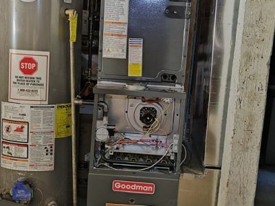 A goodman gas heater is sitting next to a water heater.