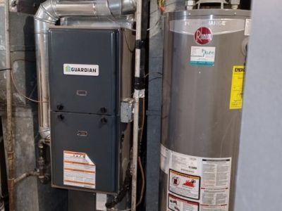 A heater and a water heater are sitting next to each other in a basement.