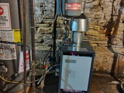A water heater is sitting in a basement next to a boiler.