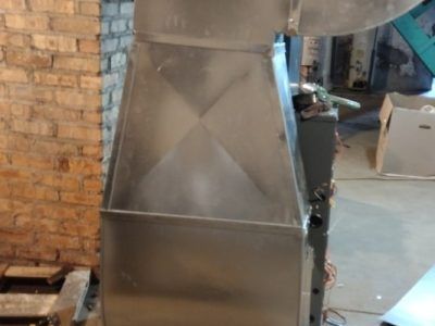 A stainless steel machine is sitting in a room next to a brick wall.