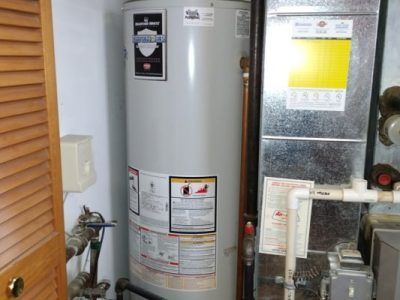 A water heater is sitting in a room next to an air conditioner