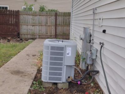 An air conditioner is sitting on the side of a house.