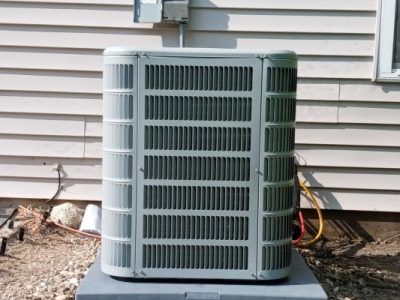 An air conditioner is sitting outside of a house.