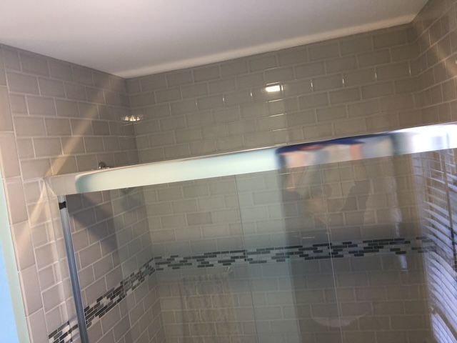 Gray-tiled shower with a clear sliding glass door and a chrome frame.