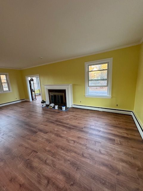 Living room with yellow walls, white trim, wood flooring, and a fireplace.