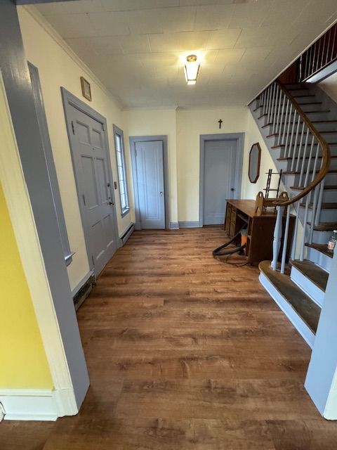 Entryway with wood floor, stairs, and three doors painted blue-gray. Yellow and white walls.
