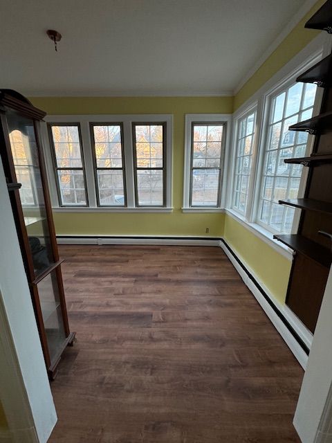 Empty room with yellow walls, wood floor, windows, and a glass cabinet.