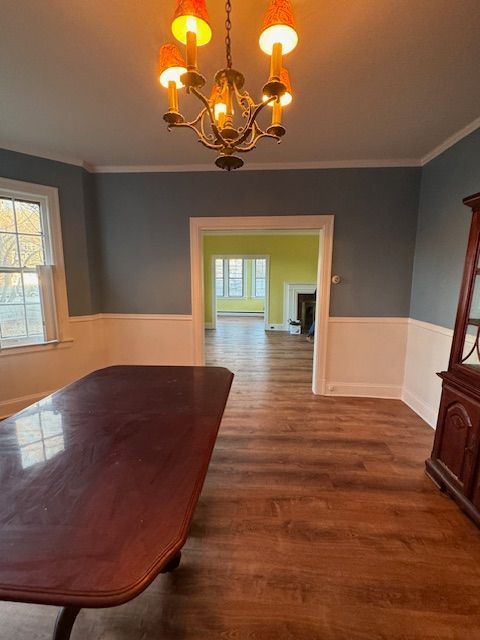Dining room with a long wooden table, chandelier, blue walls, and doorway to another room.