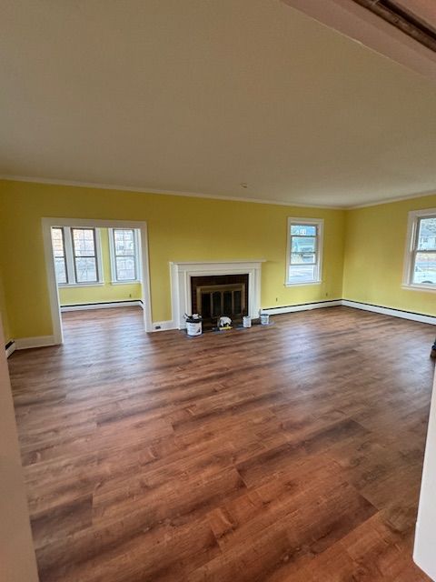 Bright yellow living room with wood flooring, fireplace, and windows.