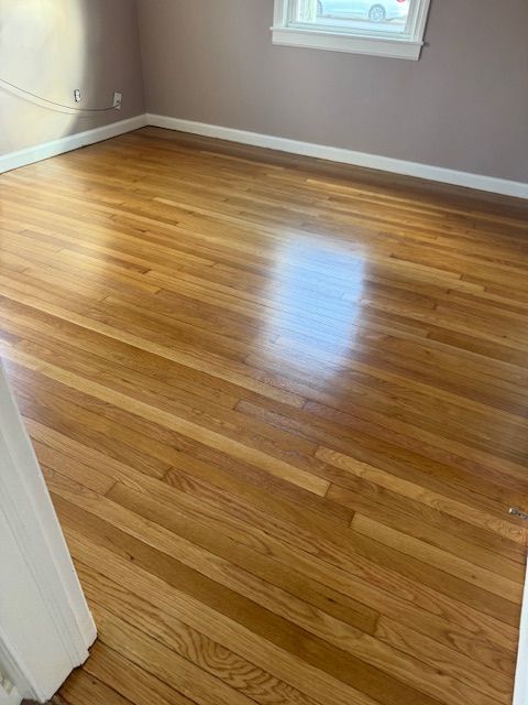 Wooden floor in a room with light-colored walls and a window.