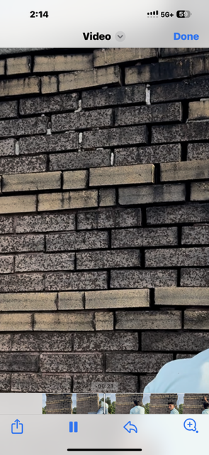 Close-up of a brick wall, with a combination of grey and tan bricks. A small amount of snow is at the bottom of the image.